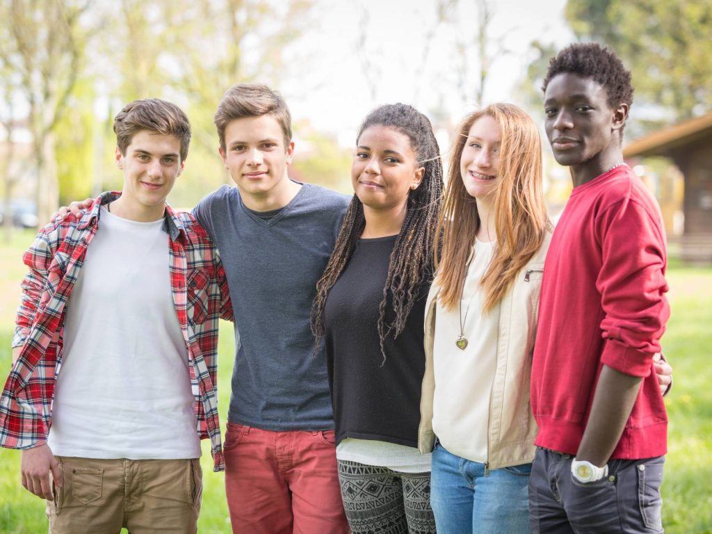 Group of five teenagers smiling and posing together